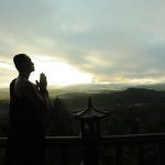 monk-holding-prayer-beads-across-mountain-2730217-min